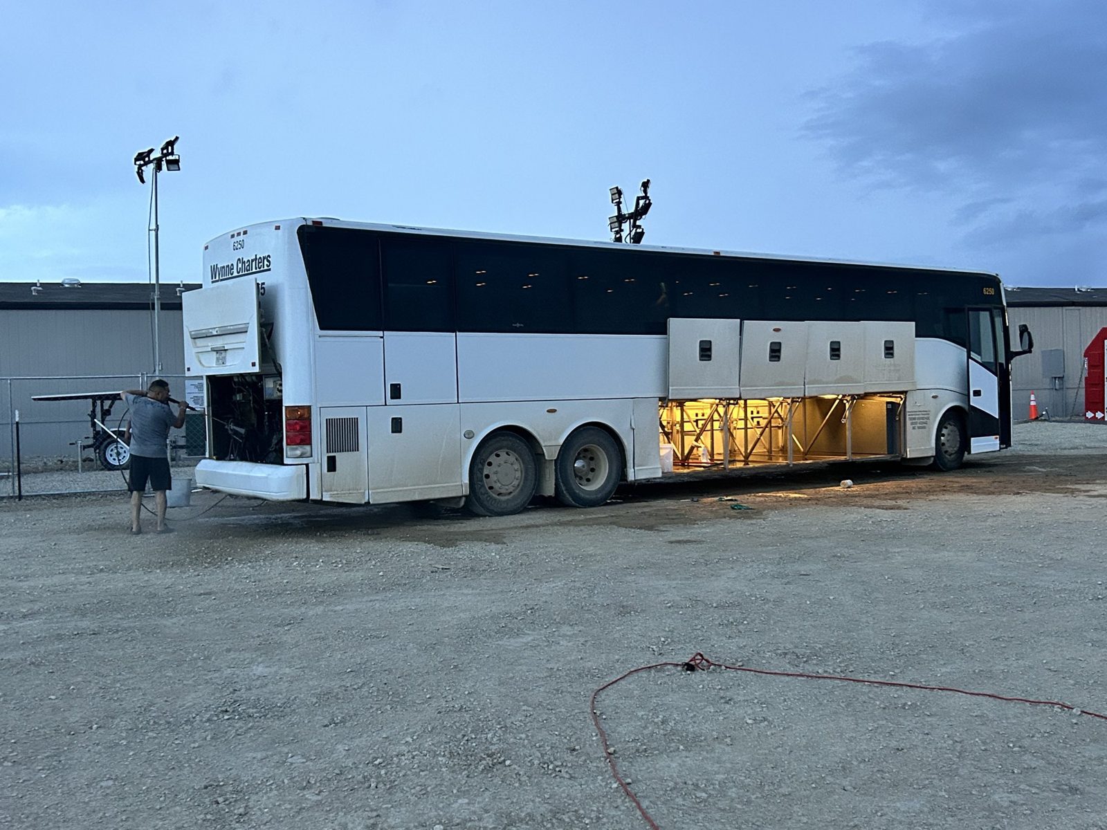 Wynne Transportation motorcoach with luggage bays open at a job site