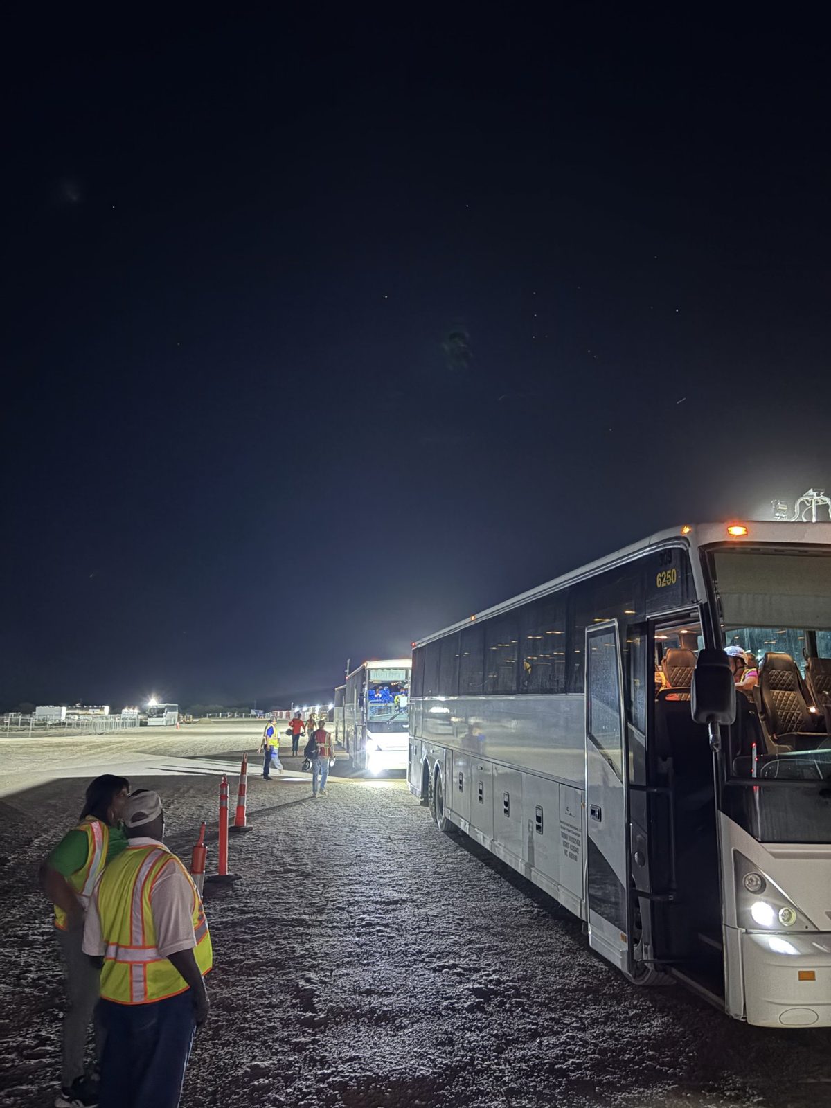 Crew member walking to a Wynne Transportation coach at a night pickup